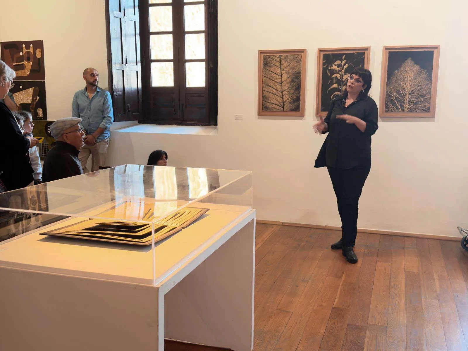 María Pujol presenta la exposición; en primer término, un libro de artista en vitrina