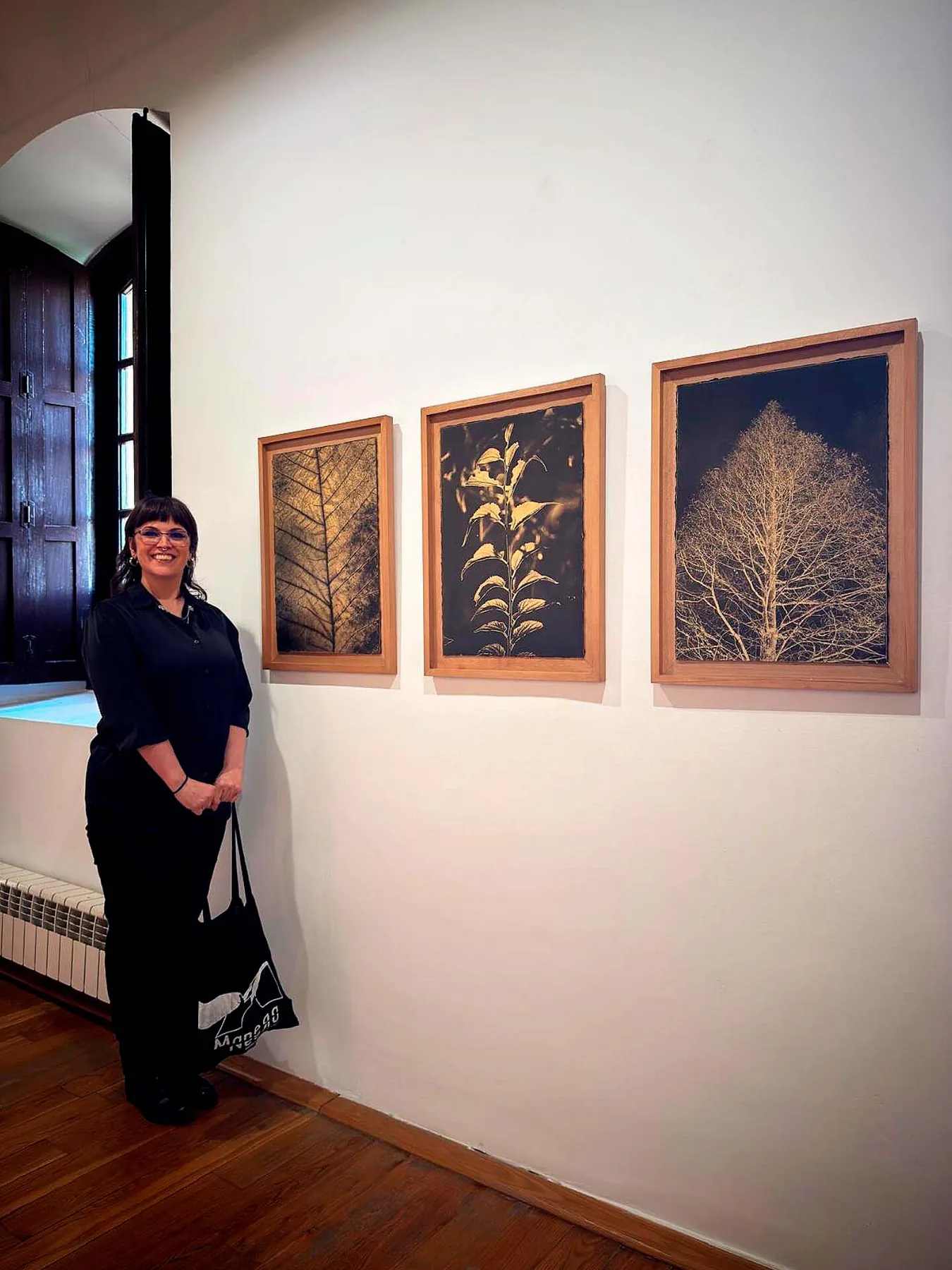 María Pujol junto a sus tres fotograbados sobre pan de oro —hoja, planta y árbol— en la exposición Summa