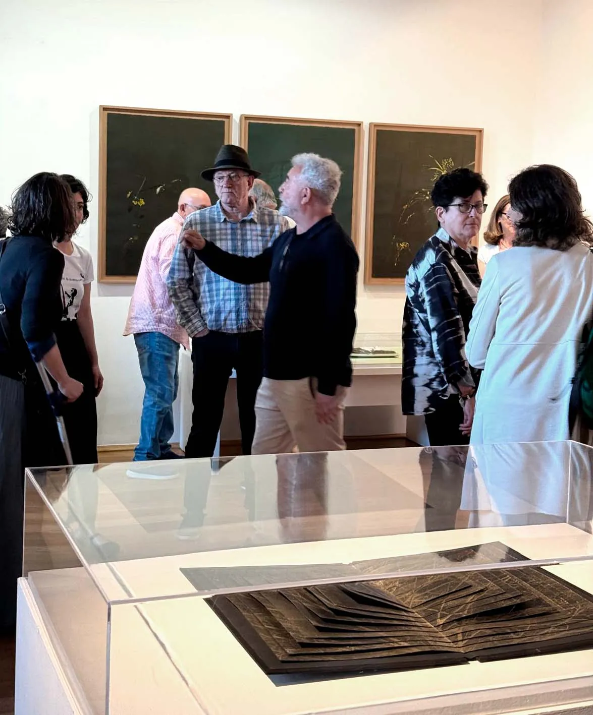 Visitantes ante la obra de María Pujol y un libro de artista en vitrina